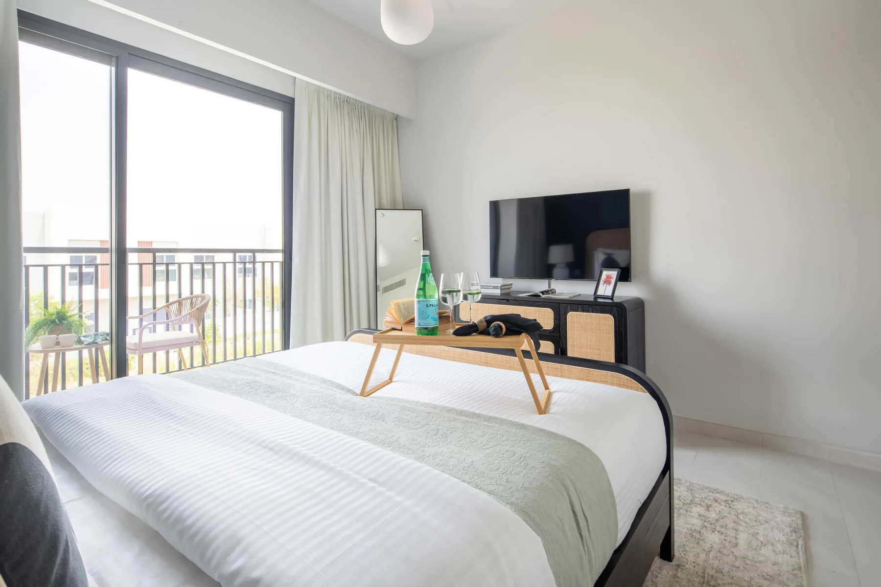 Un dormitorio luminoso con una cama frente a un televisor y puertas corredizas de vidrio.