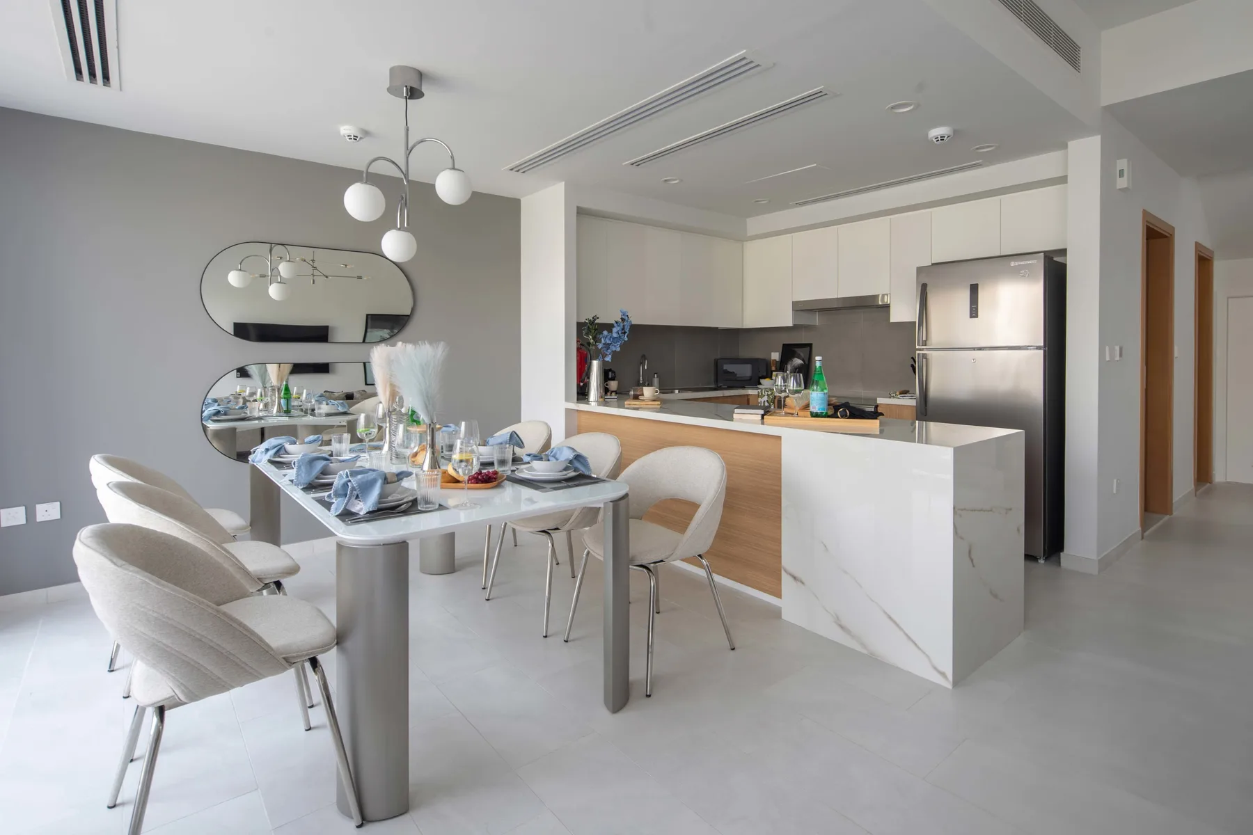 Comedor con la mesa puesta junto a una cocina abierta y una barra.