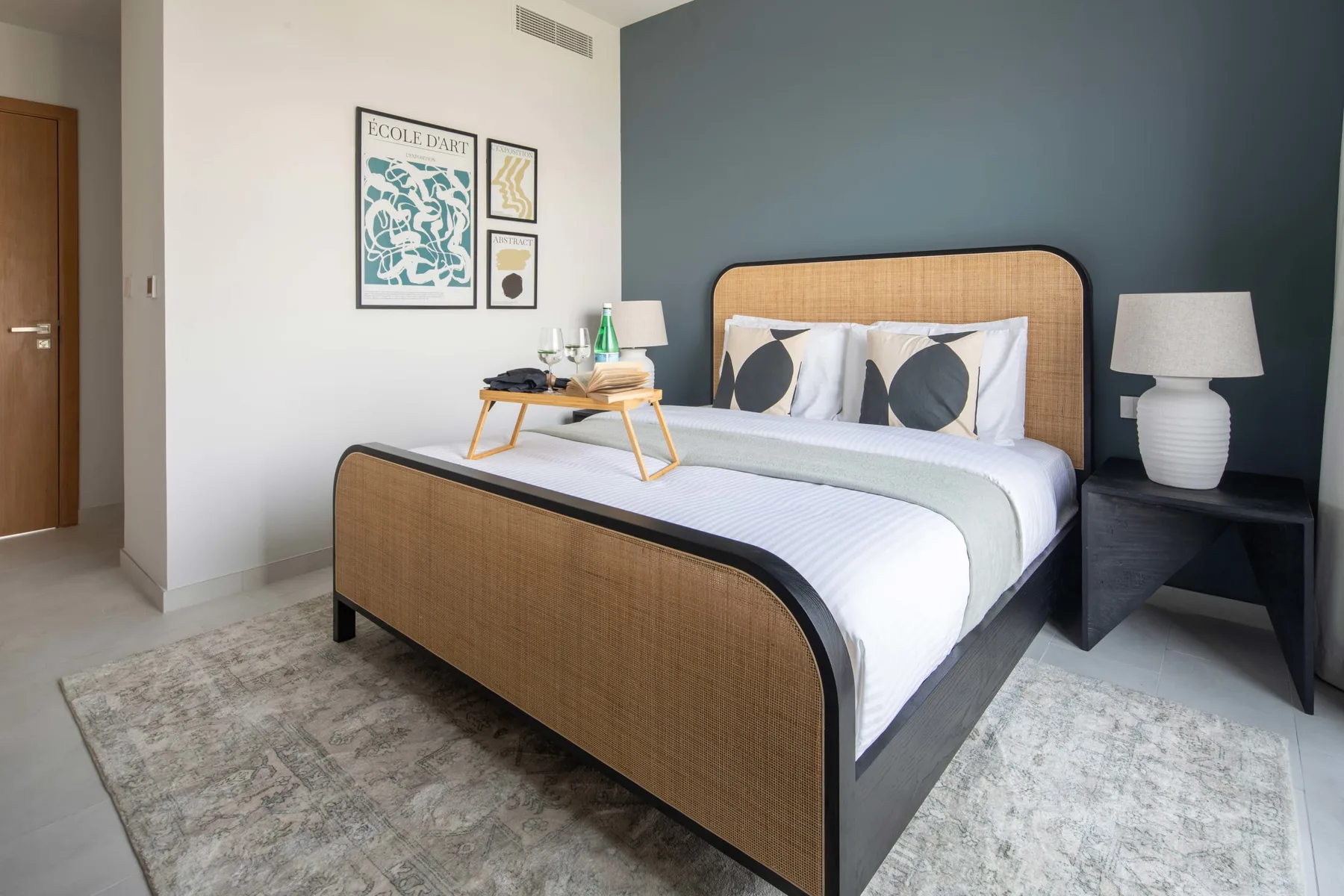 Un dormitorio con una cama junto a una pared oscura y cuadros enmarcados.