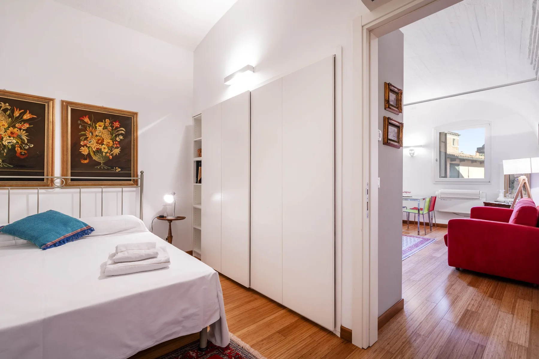 A bright bedroom with a neatly made bed and an adjoining sitting area.