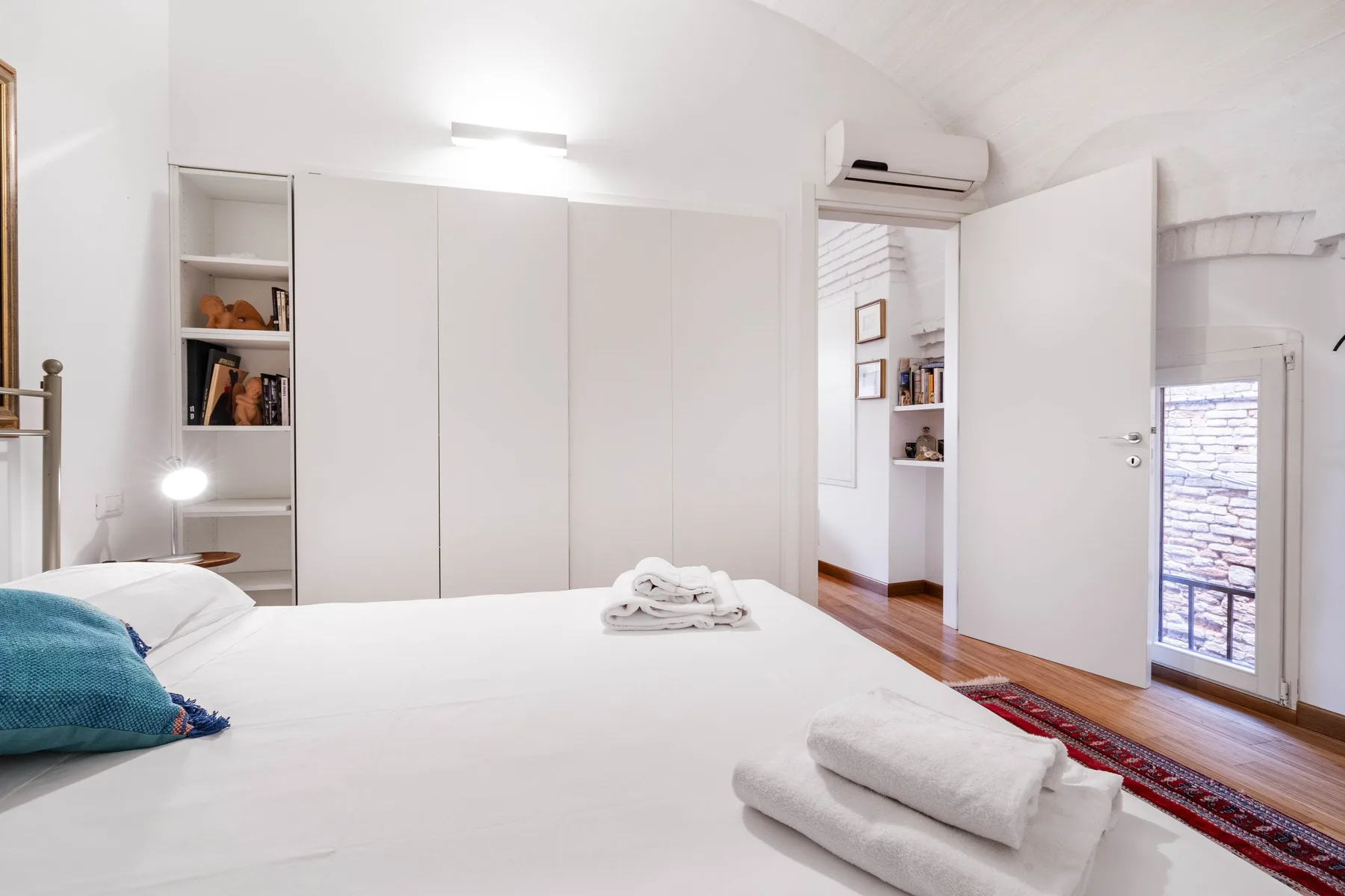A bright bedroom with a large bed and an open doorway.
