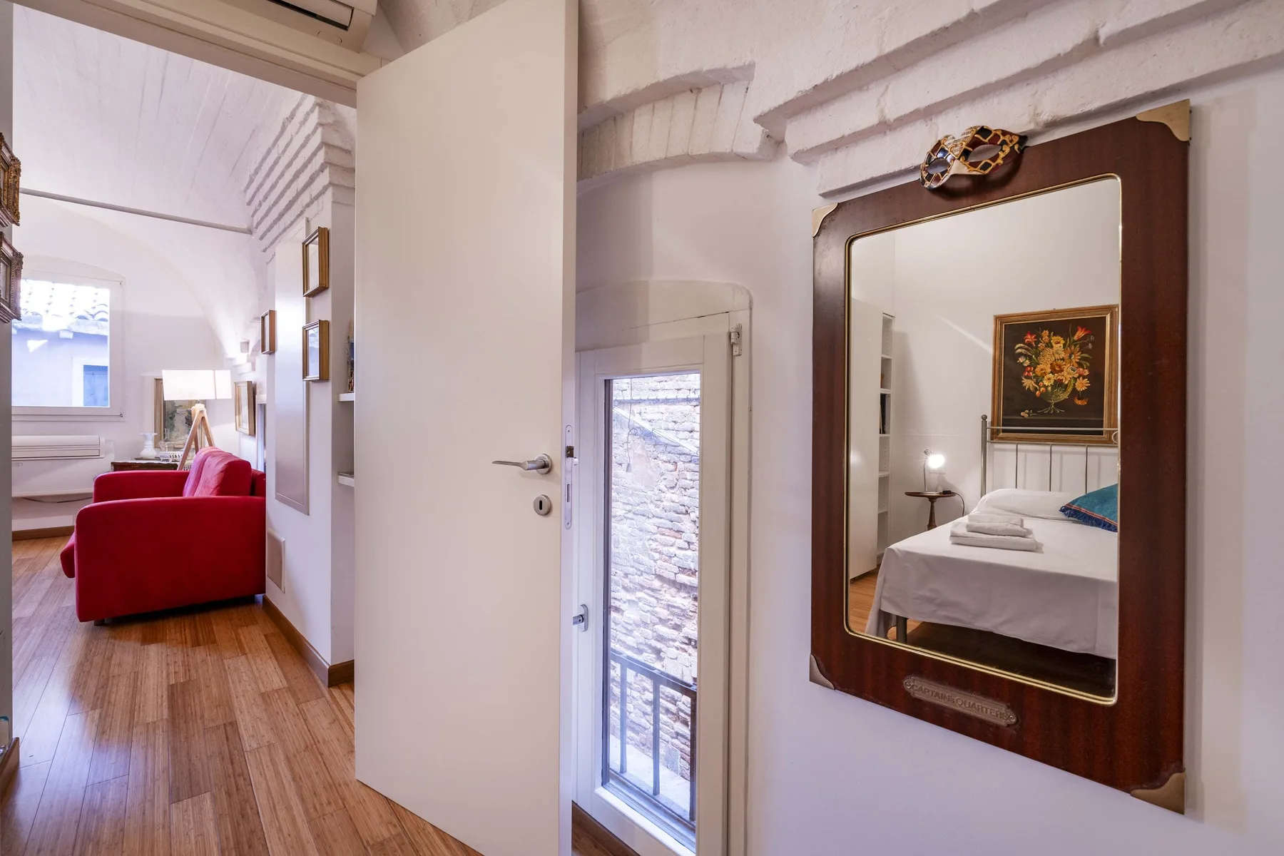 A bedroom is visible in a large wall mirror beside an open doorway.