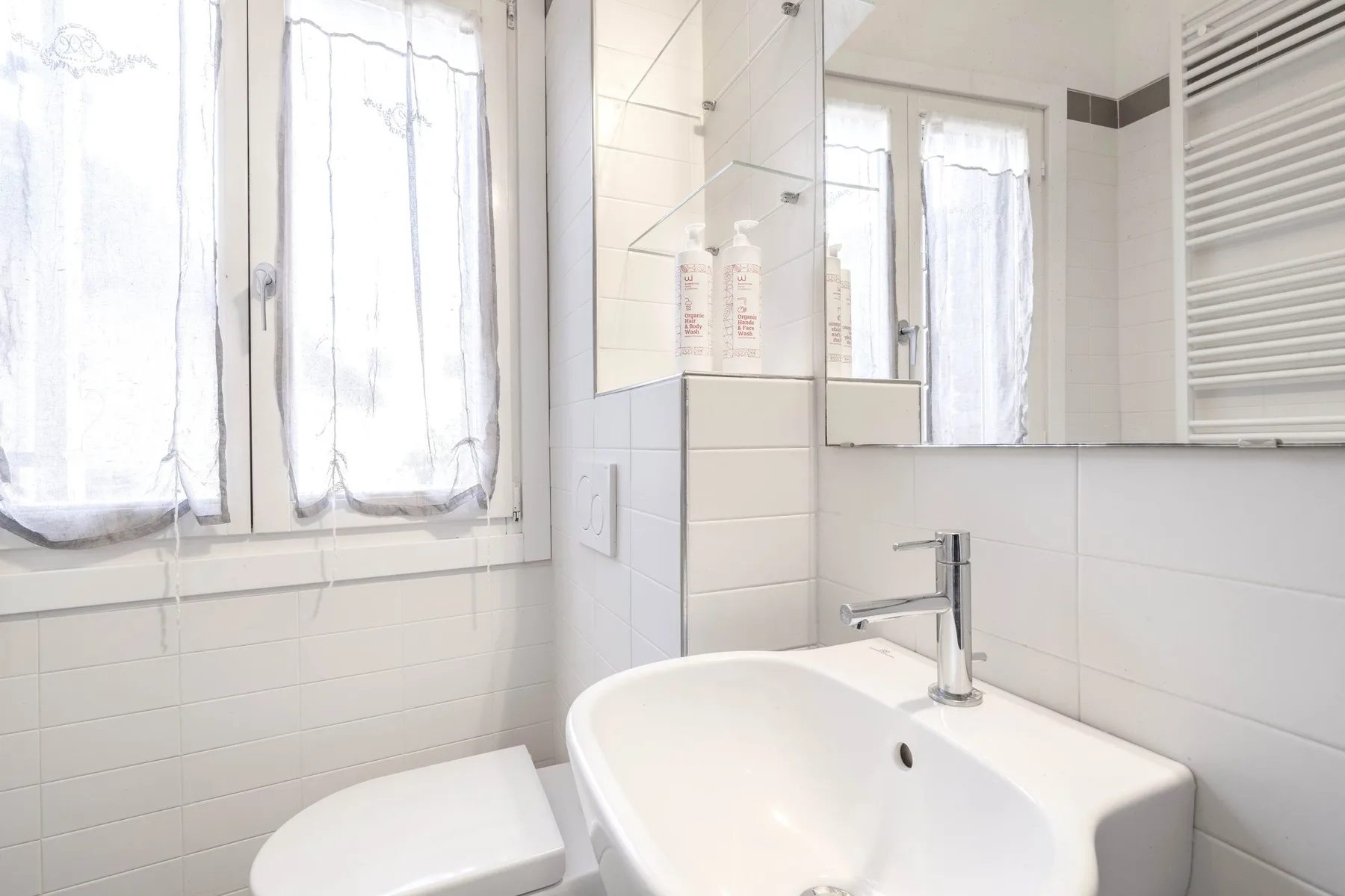 A bright bathroom with a white sink and windows.