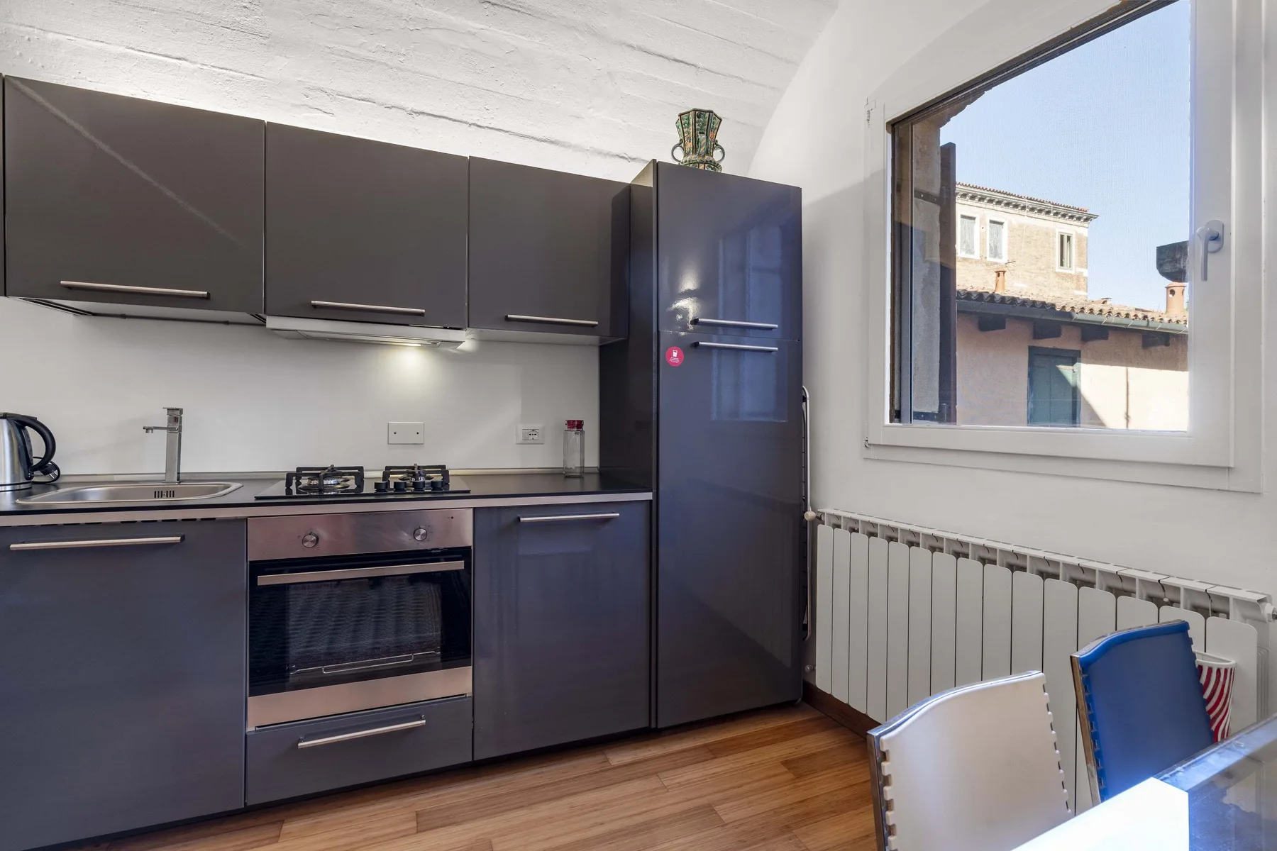 A modern kitchen with dark cabinets, a stove, and a window.