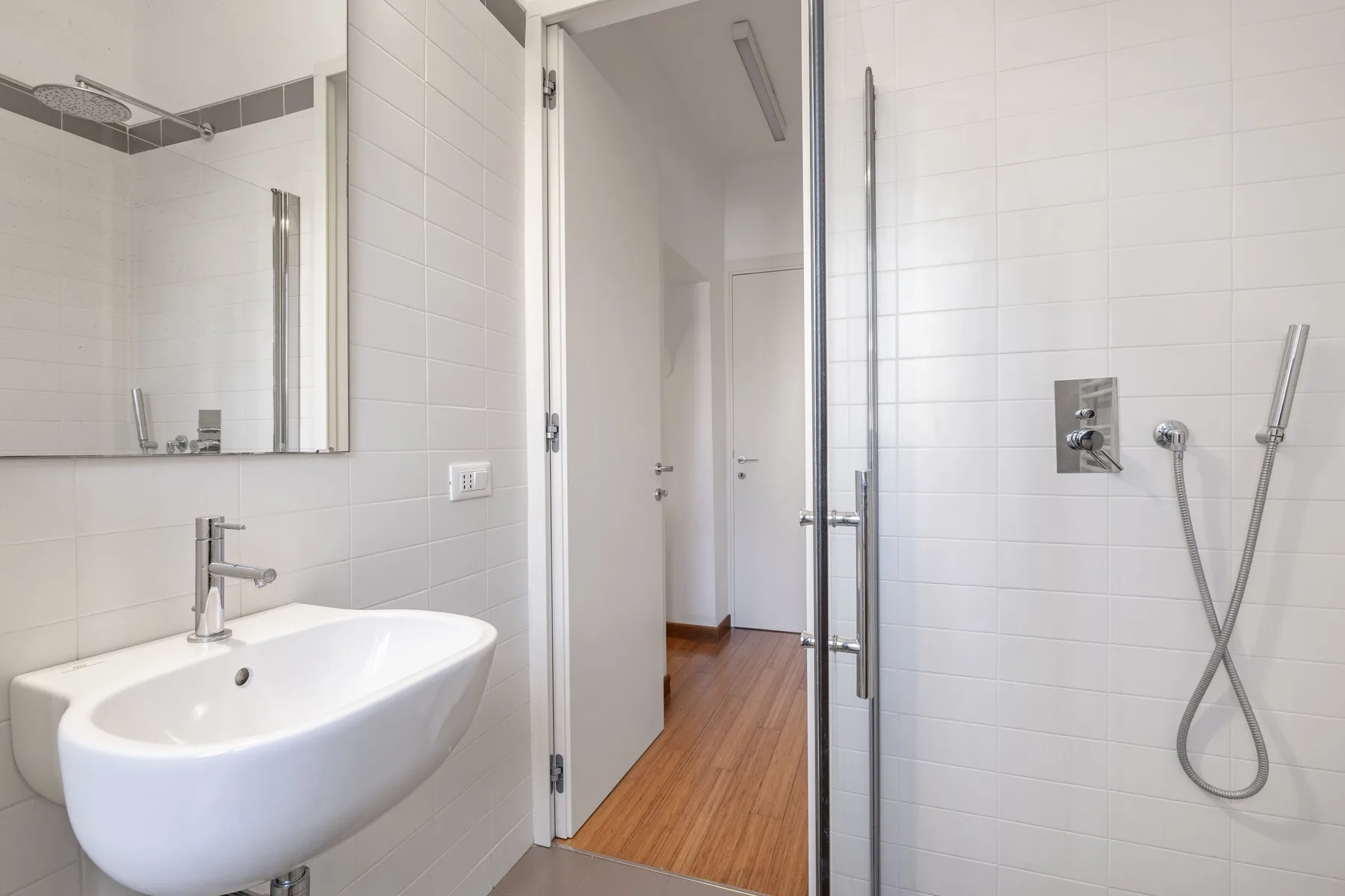A bright tiled bathroom with a sink and shower.