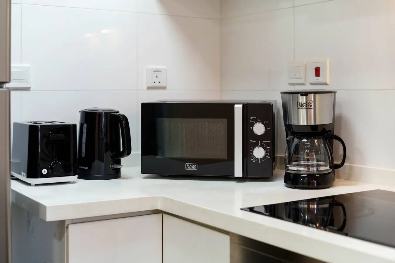 A kitchen counter holds small appliances beside a built-in cooktop.