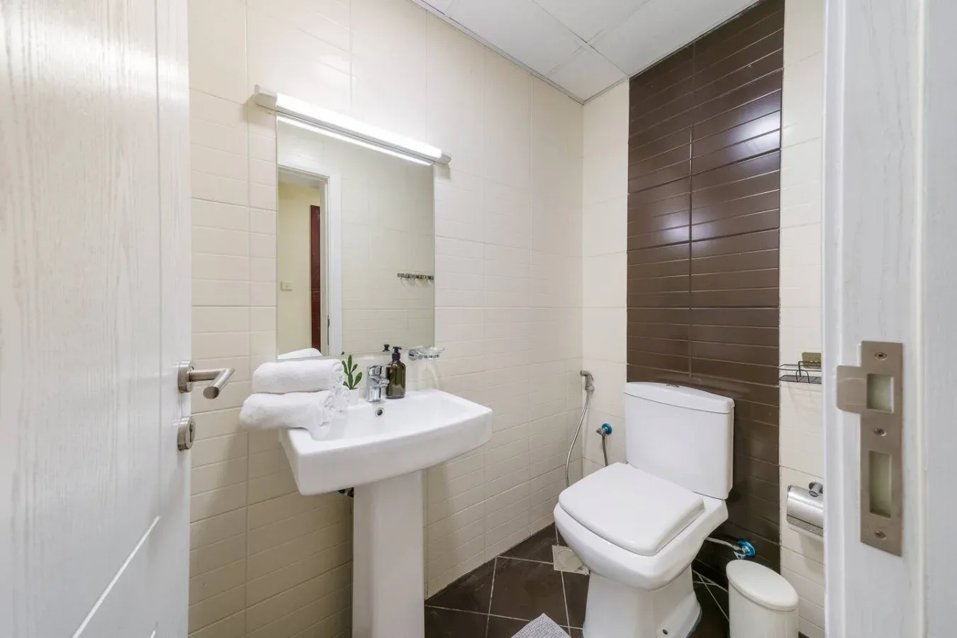 A bathroom with a wall-mounted sink, mirror, and toilet.