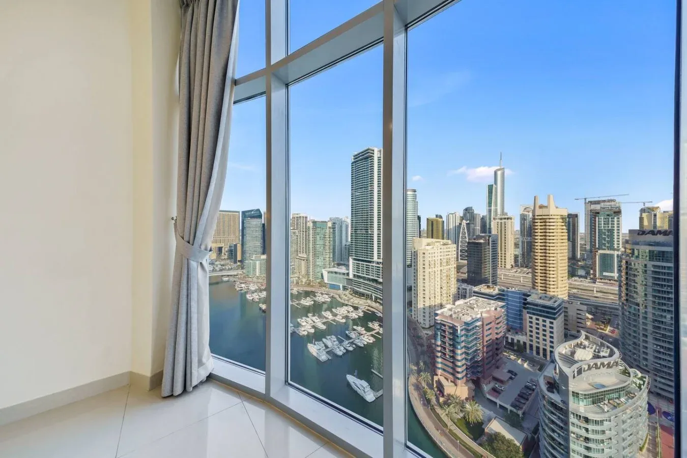 Floor-to-ceiling windows overlook a city skyline and marina.