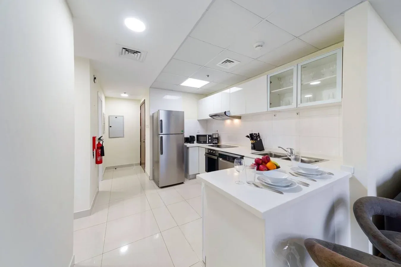 A bright kitchen with white cabinets, stainless steel appliances, and a breakfast counter.