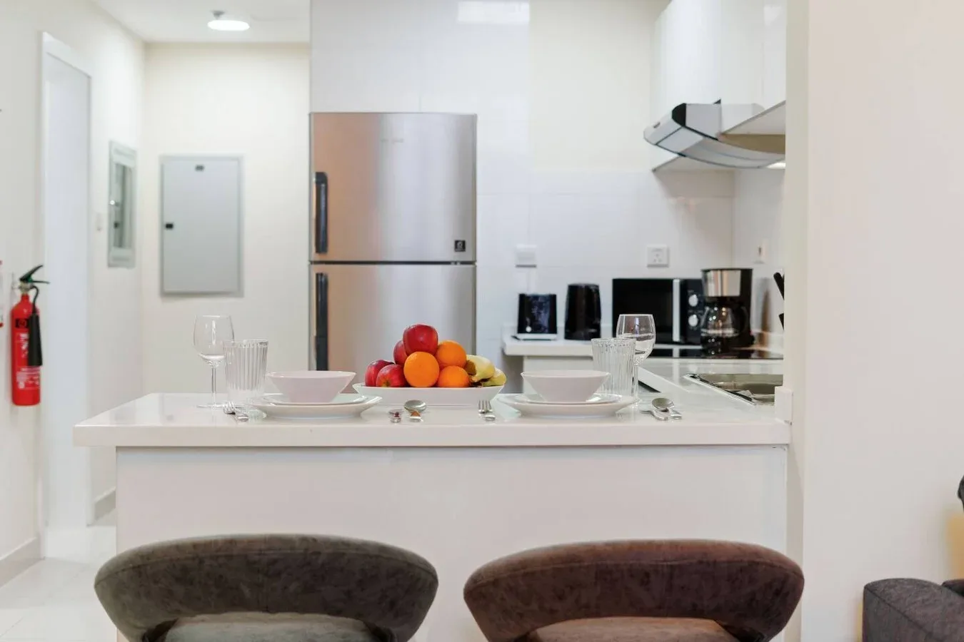A bright kitchen with a counter displaying a bowl of fruit.