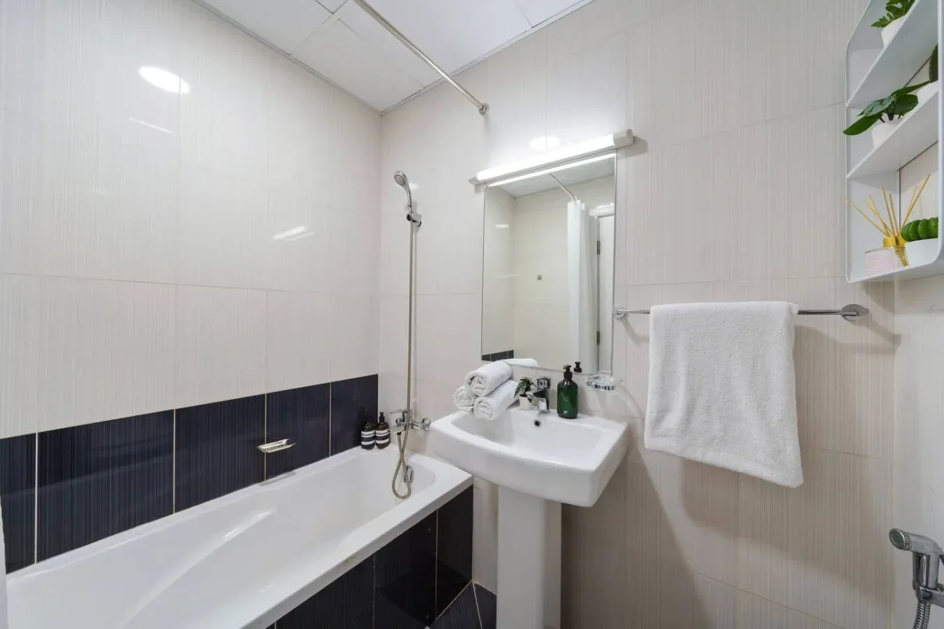 A tiled bathroom with a bathtub, shower, and wall-mounted sink.