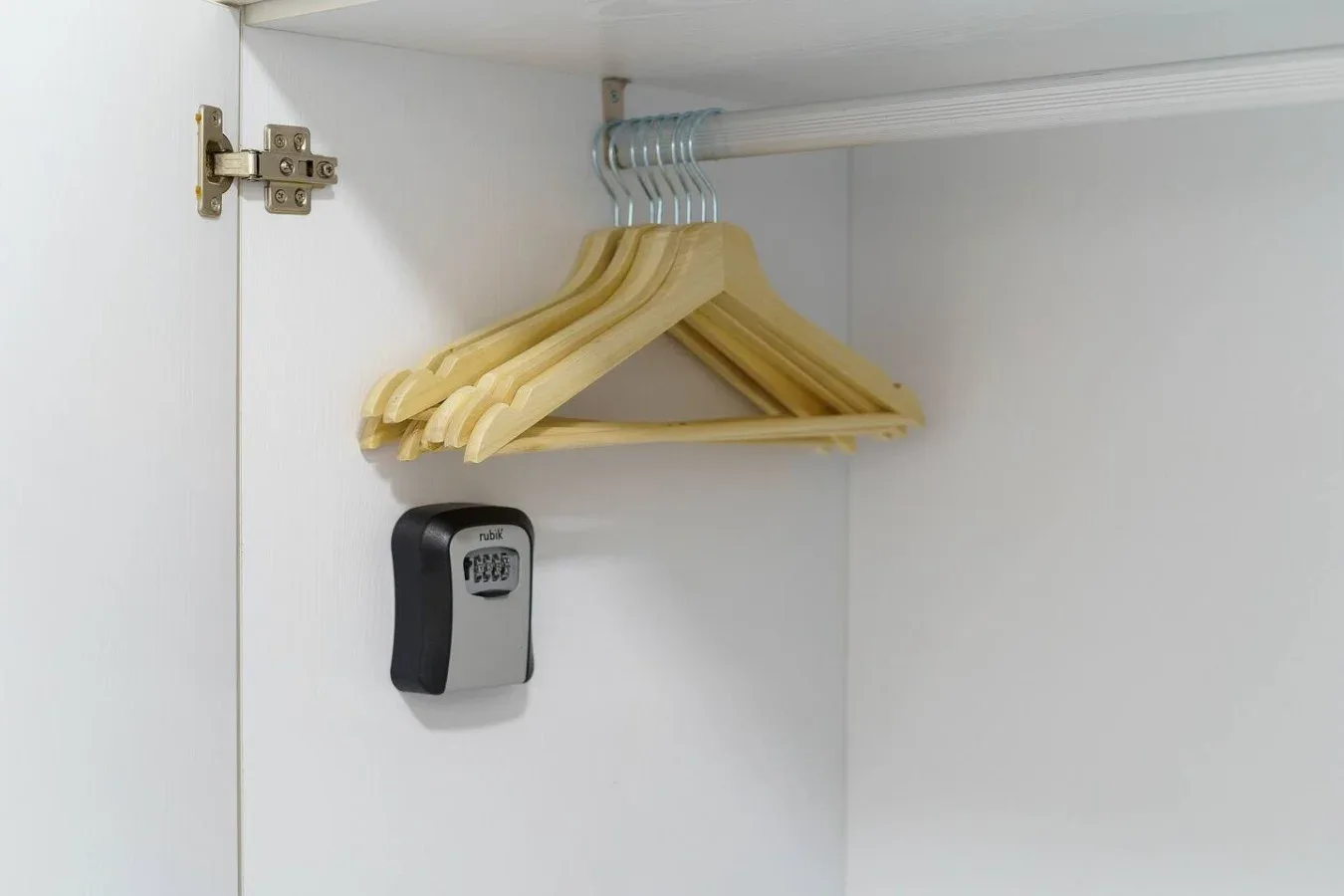 An open wardrobe with wooden hangers and a wall-mounted device.