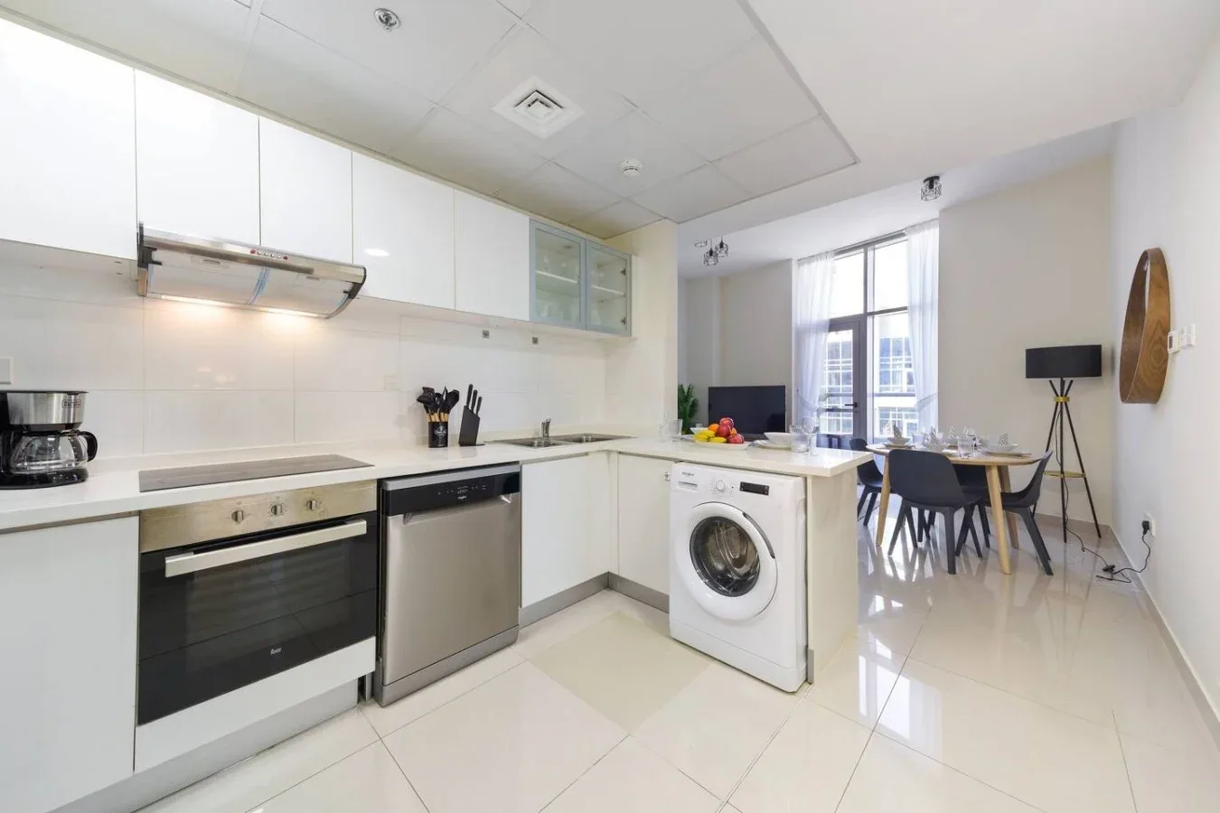 A modern kitchen opens into a dining area with a table and chairs.