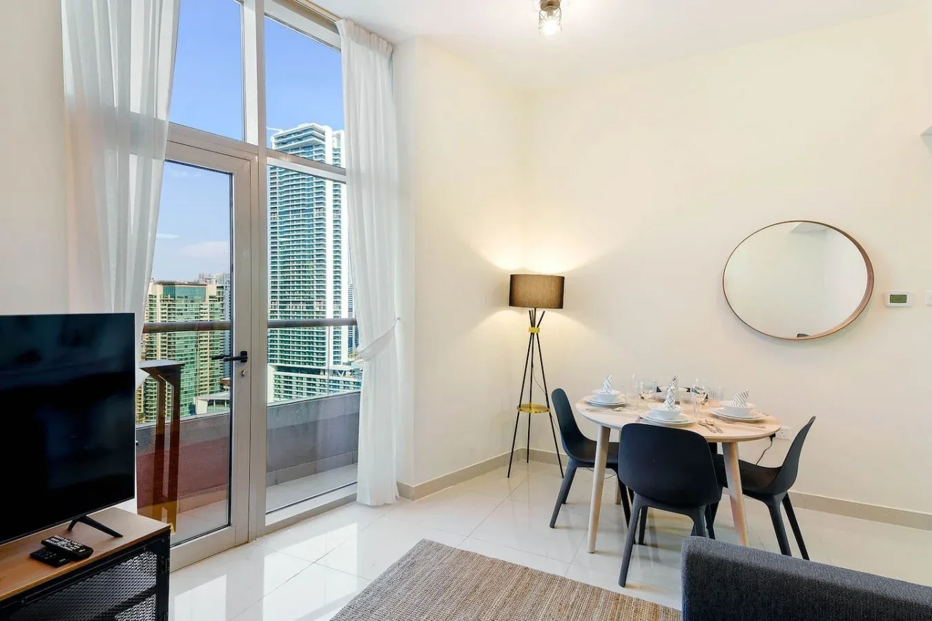 A dining area beside floor-to-ceiling windows, with a table set for a meal.