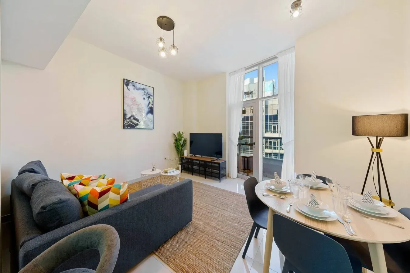 A bright living and dining area with a sofa, table, and large windows.