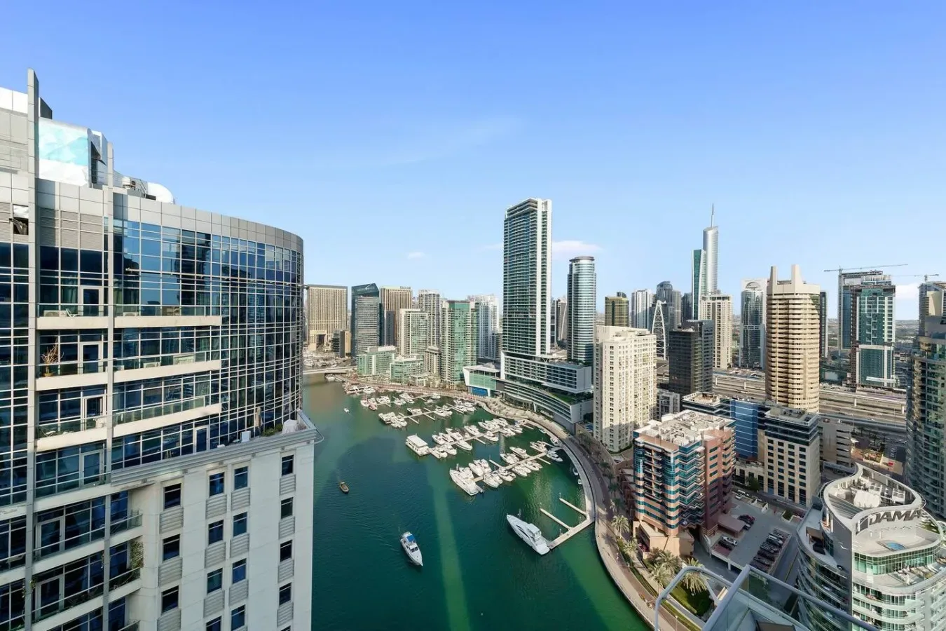 A waterfront city skyline rises around a marina filled with boats.