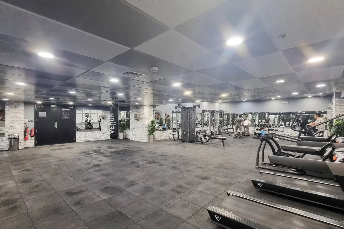 A spacious gym with exercise machines, weights, and a mirrored wall.