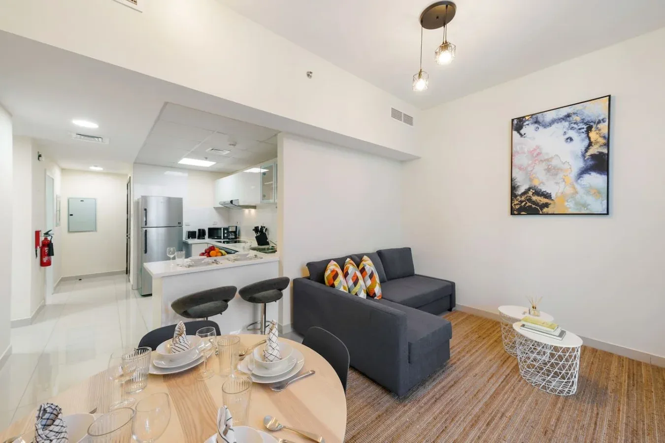 An open-plan living and dining area with a kitchen counter and gray seating.