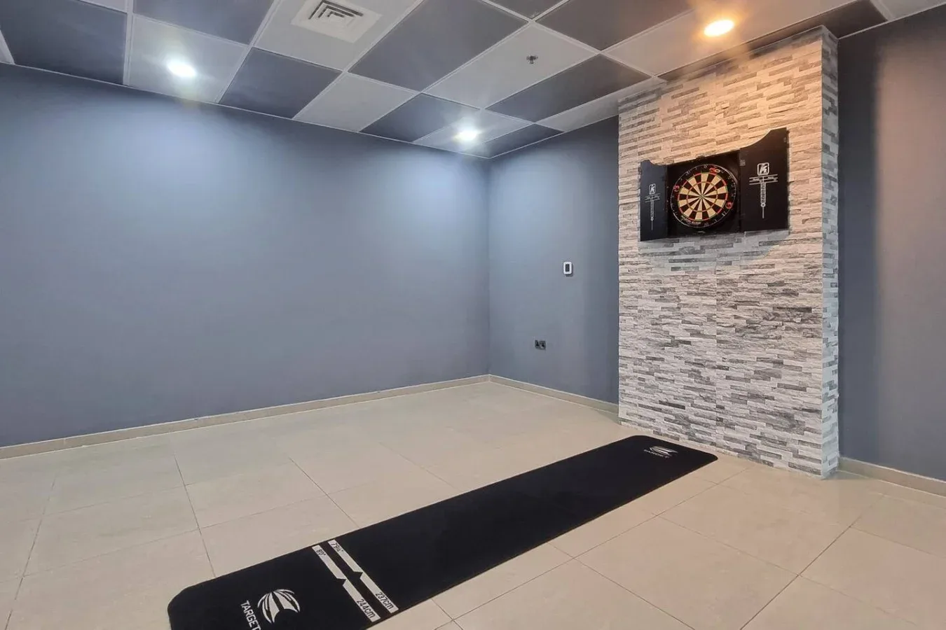 A recreation room with a dartboard mounted on a stone-patterned wall.