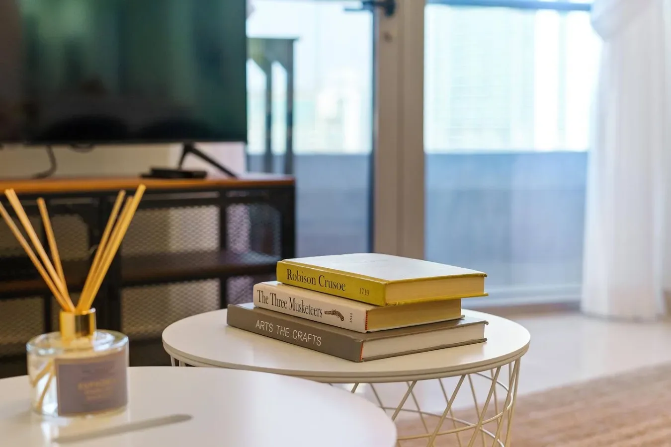 A living room with books on a round coffee table beside a television.