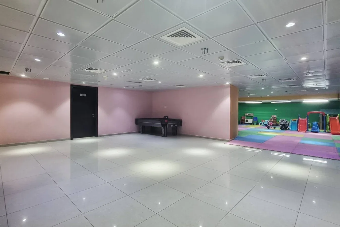 An open indoor recreation area has a tiled floor and a colorful play space.