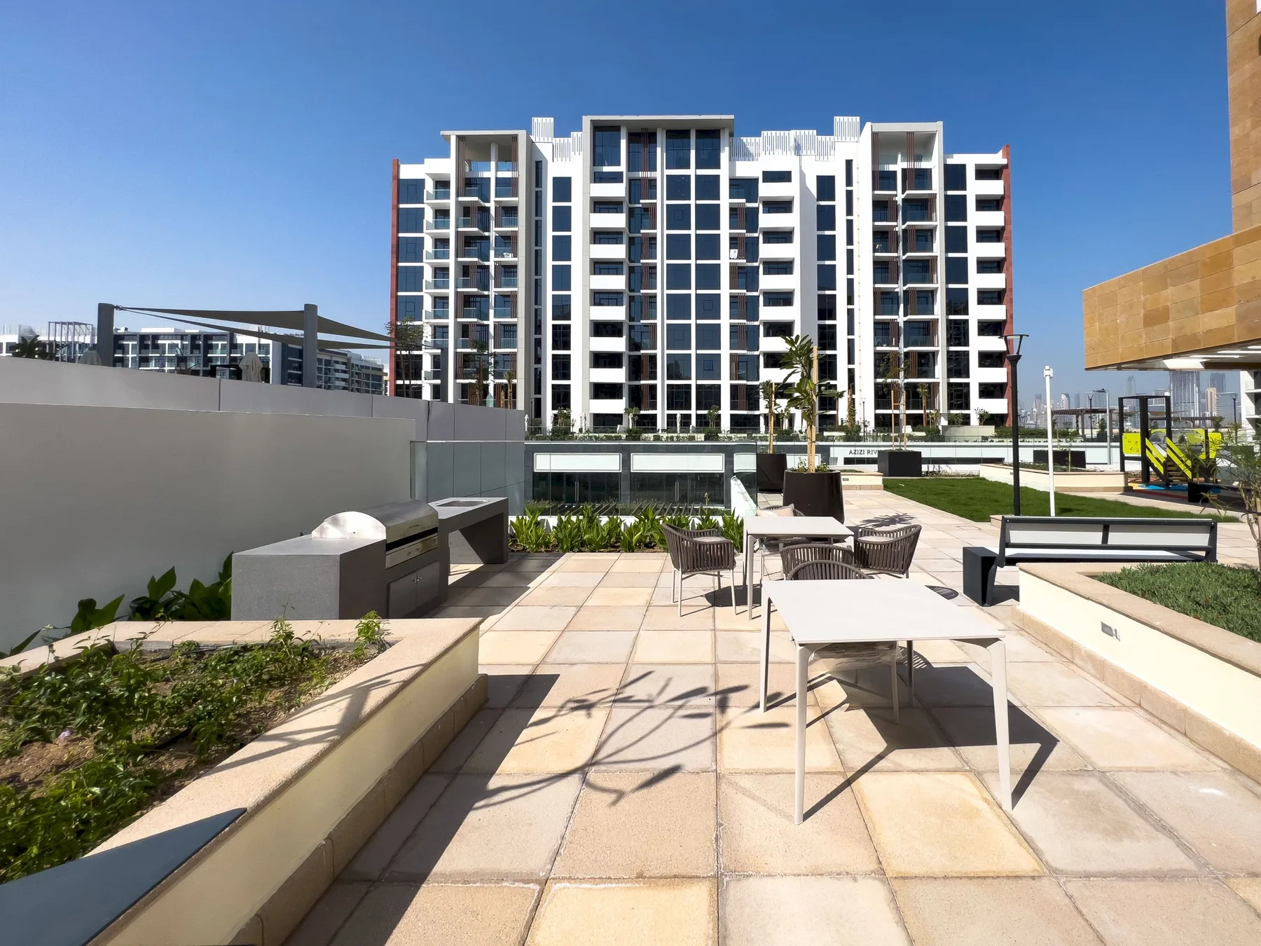Una terraza al aire libre con asientos da a un moderno edificio de apartamentos.