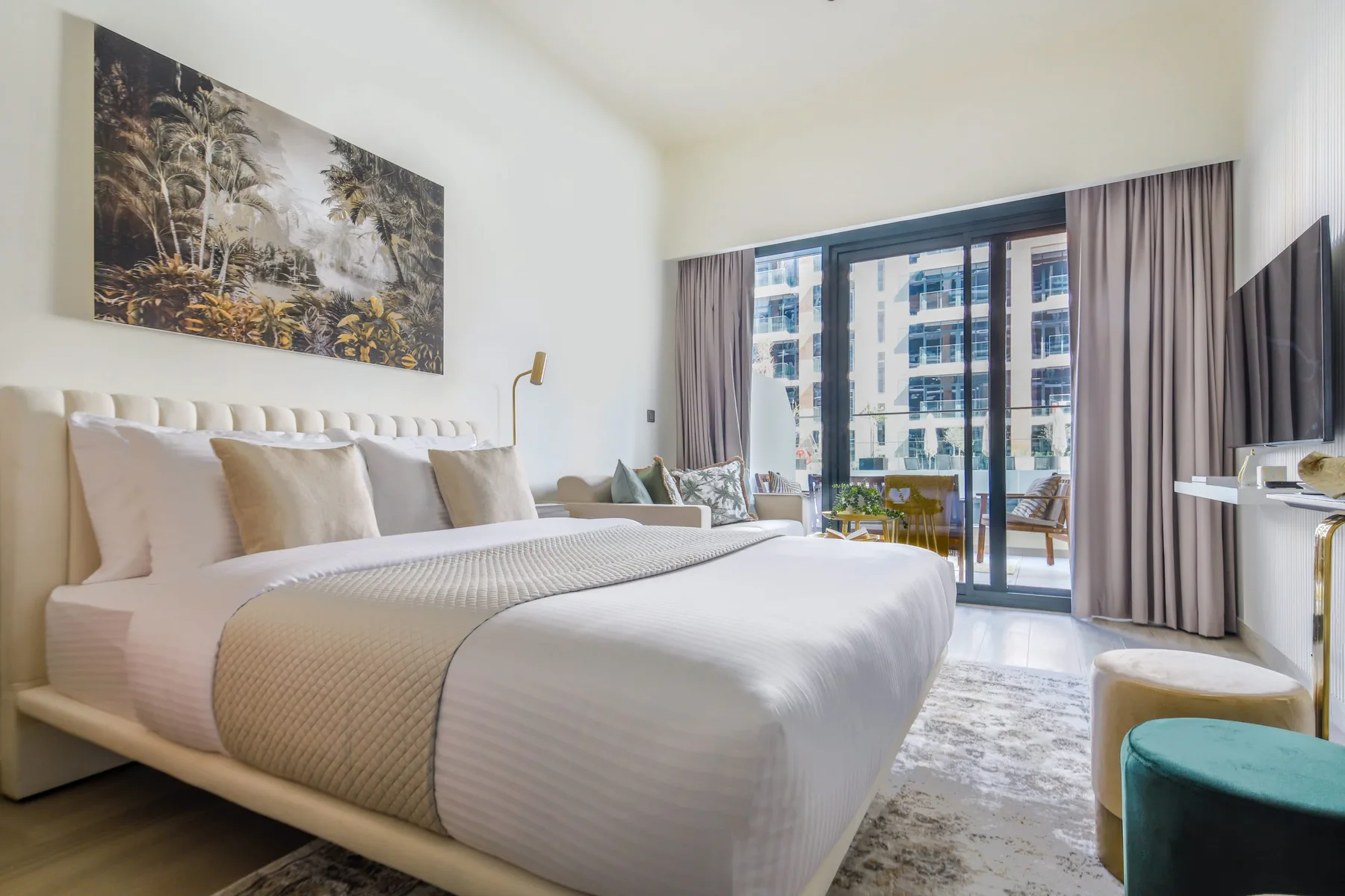 Un dormitorio luminoso con una cama bien tendida y puertas corredizas de vidrio hacia un balcón.