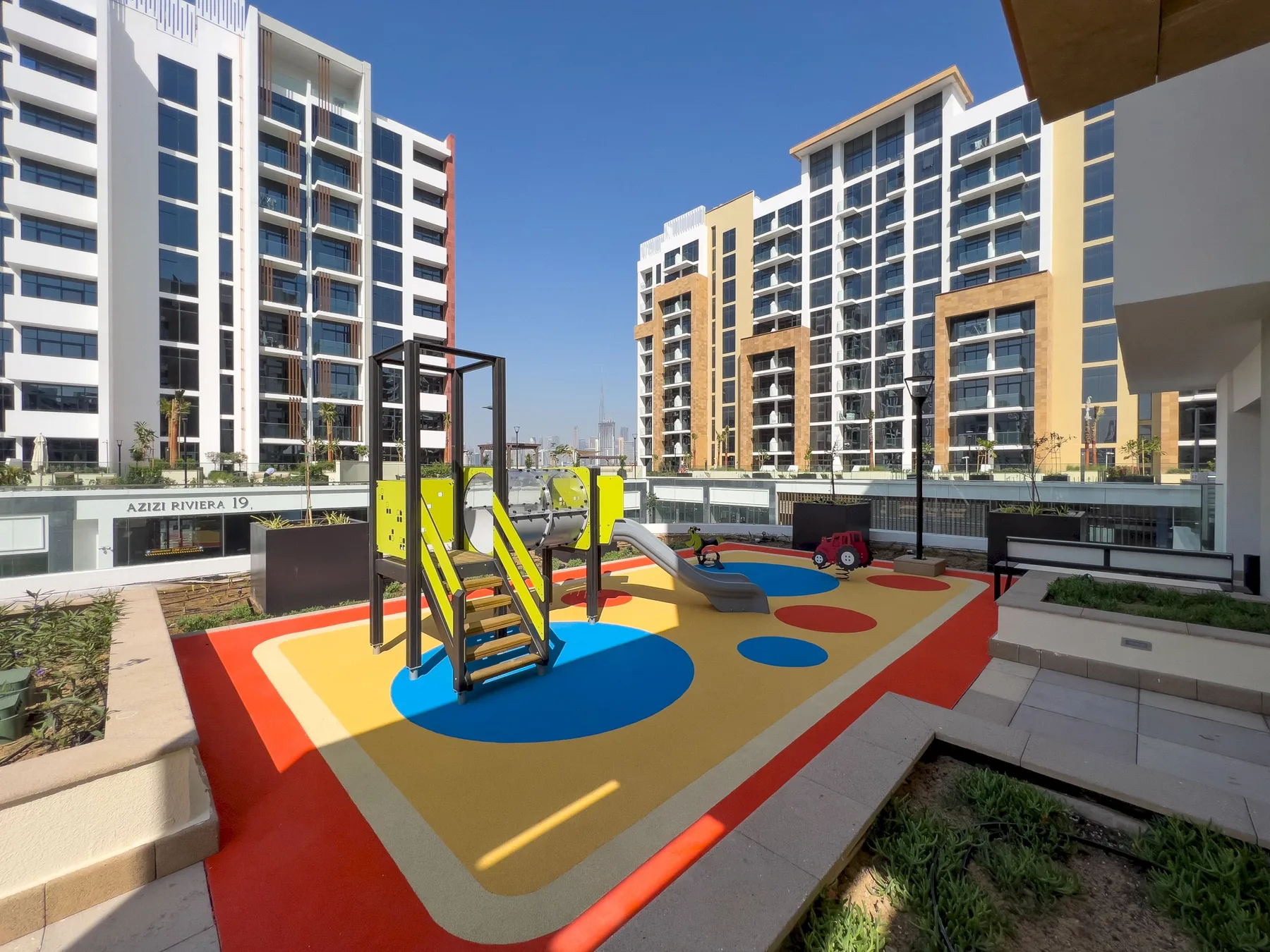 Un colorido parque infantil al aire libre está entre edificios de apartamentos modernos.