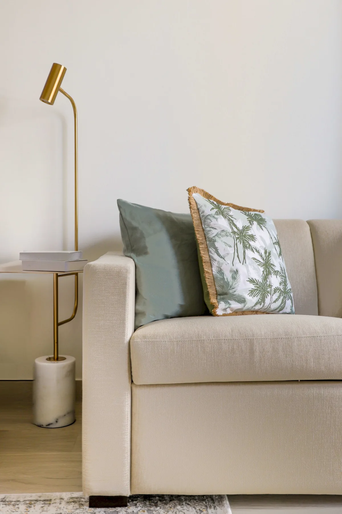 A light-colored sofa with decorative cushions sits beside a slim floor lamp.