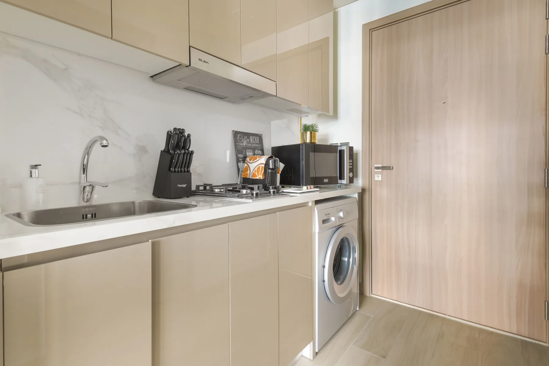 Una cocina moderna con fregadero, electrodomésticos sobre la encimera y lavadora.