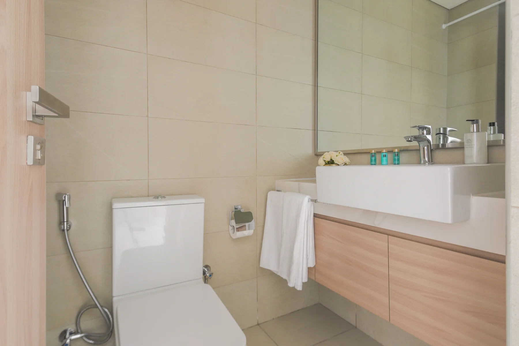 Un baño con azulejos, inodoro, lavabo suspendido y espejo.