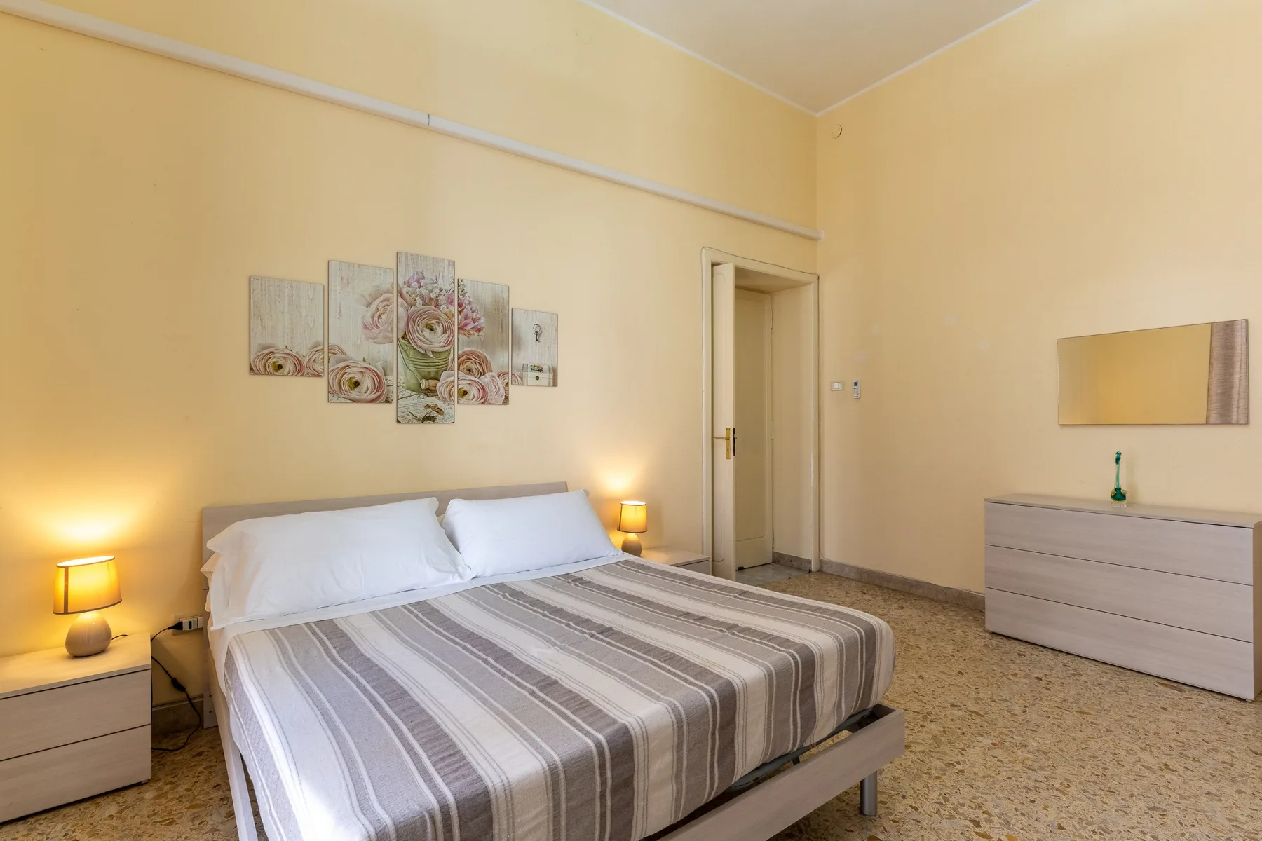 Un dormitorio con una cama doble, lámparas de mesilla y cuadros en la pared.