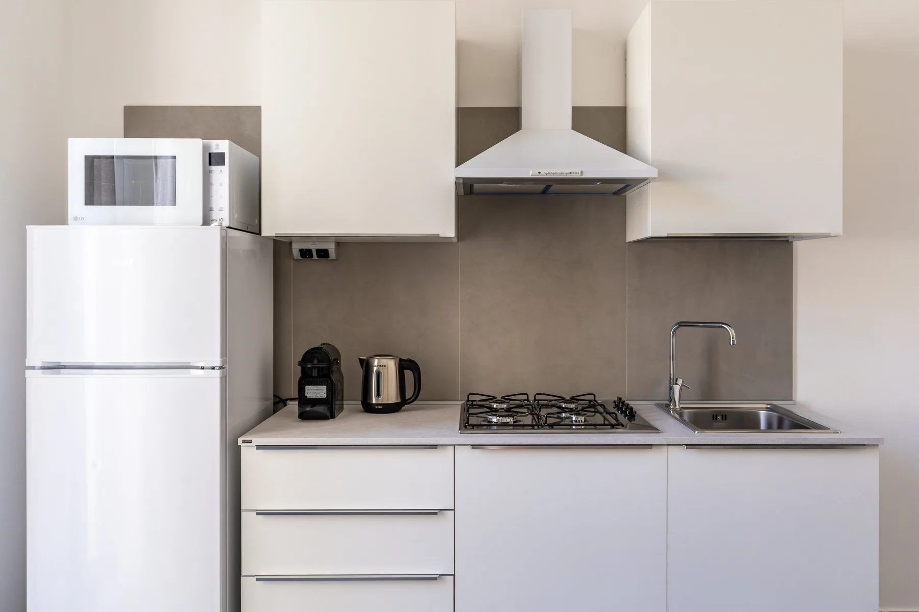 A modern kitchen with white cabinetry, a gas cooktop, and a sink.