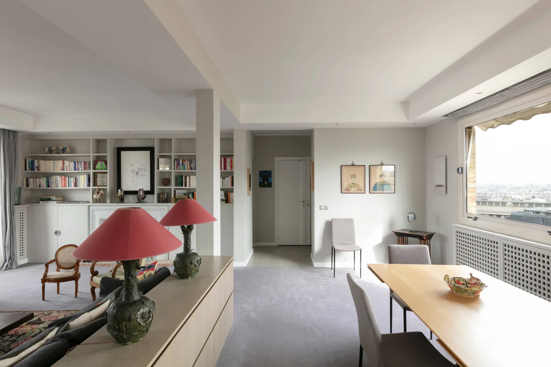 A bright living and dining area with a long table beside large windows.