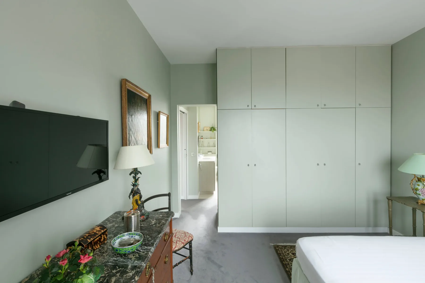 A bedroom with a bed, built-in cabinets, and a wall-mounted television.