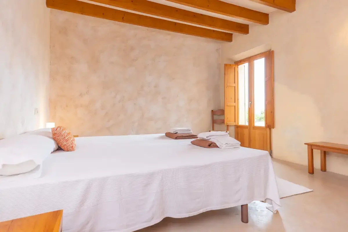 A bedroom with a neatly made bed and an open wooden window.