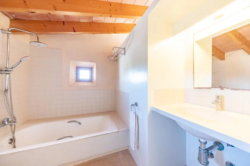 A bathroom with a bathtub and a sink beneath a large mirror.