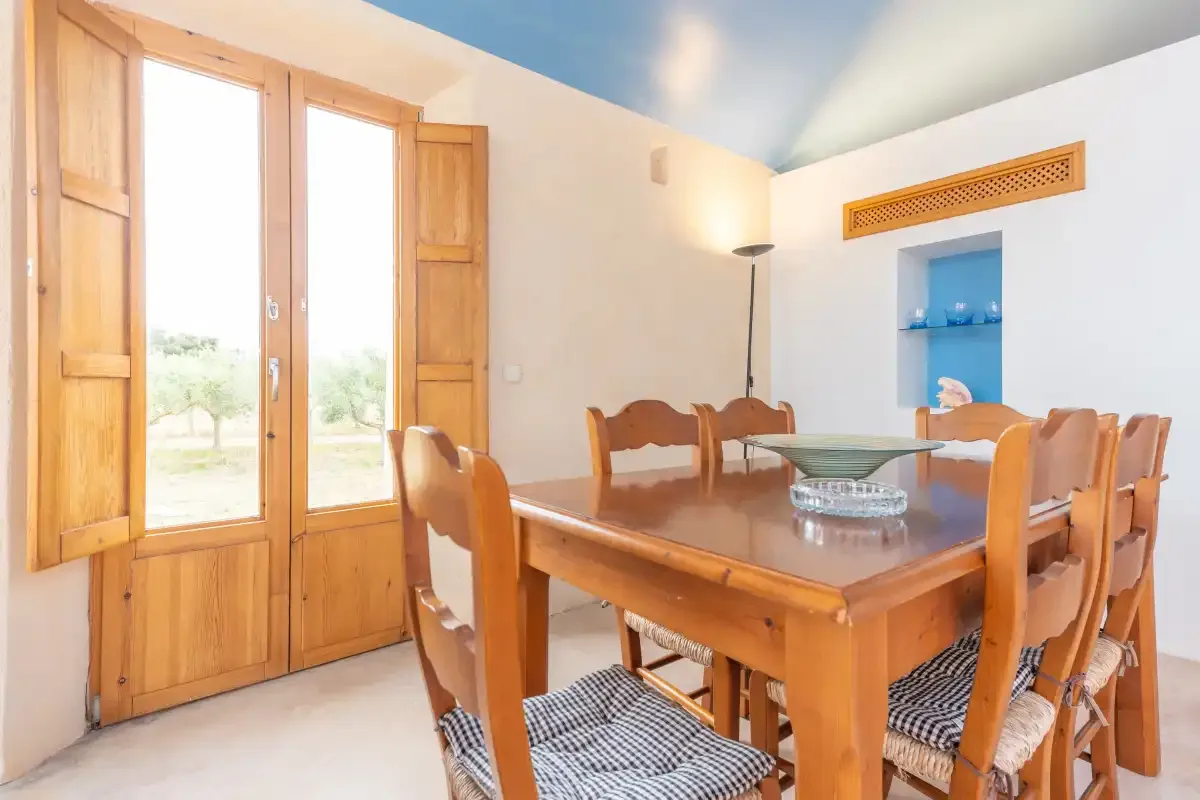 A dining room with a wooden table and seating beside tall windows.
