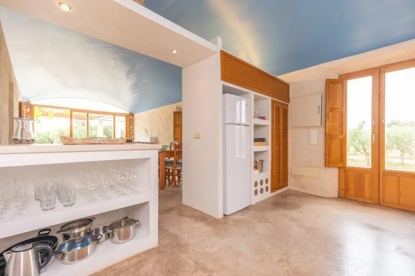 A bright kitchen with open shelving and wooden-framed windows.