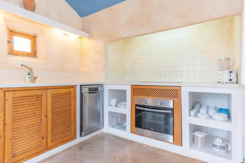 A kitchen with a sink, dishwasher, oven, and open shelving.