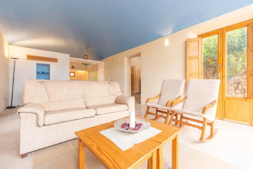 A bright living room with a sofa, two chairs, and a wooden coffee table.