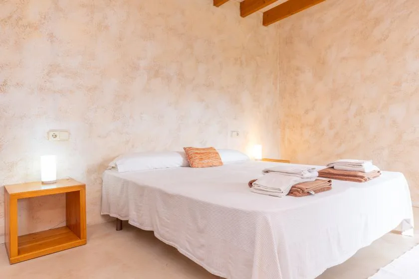 A bedroom with a double bed, bedside table, and folded towels.