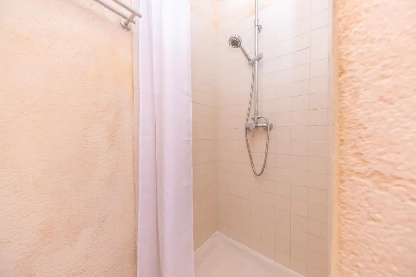 A tiled shower area with a handheld showerhead and a curtain.