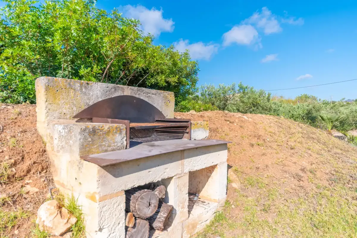 An outdoor stone oven stands beside a dry hillside.