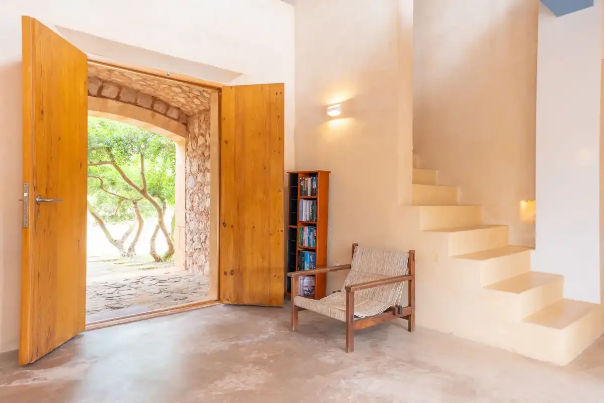 A bright entry hall with open wooden doors and a staircase.