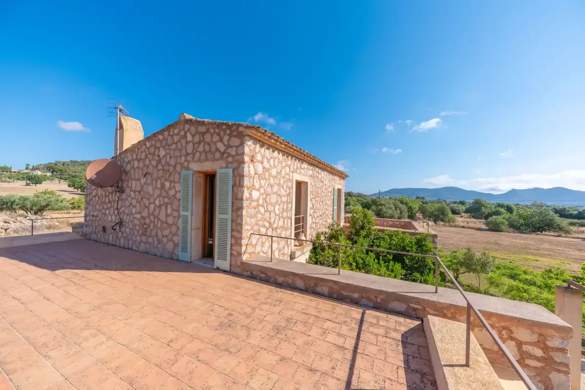 A stone house opens onto a broad terrace overlooking the countryside.
