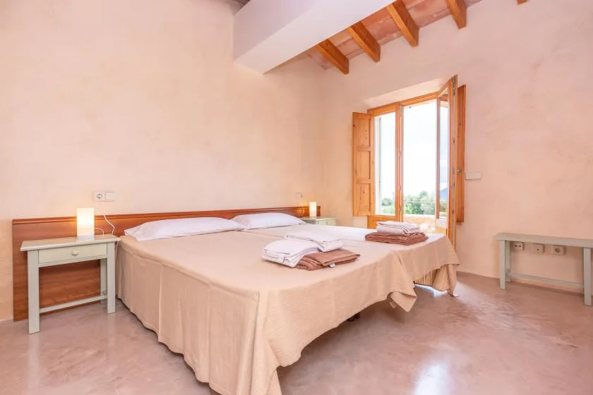 A bedroom with a large bed, folded towels, and an open window.