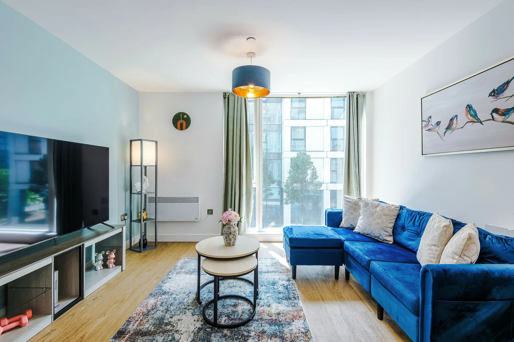 A bright living room features blue seating beside a large window.