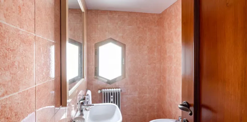 Un baño alicatado con lavabo, espejo y radiador.