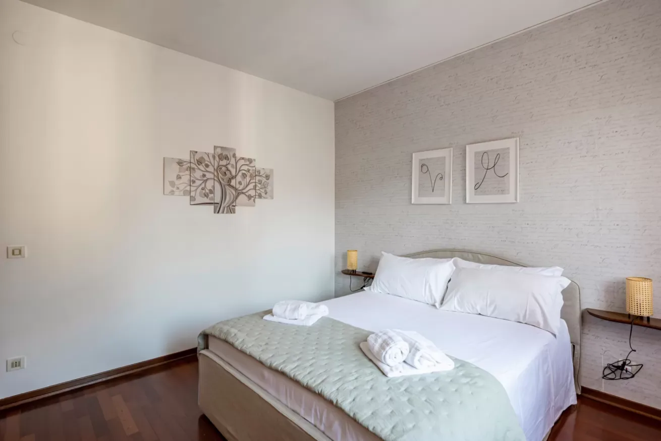 Un dormitorio con una cama bien tendida y cuadros en las paredes.